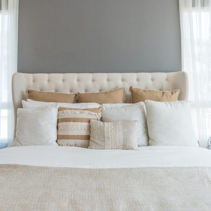 Bedroom in soft light colors. big comfortable double bed in elegant classic bedroom at home.