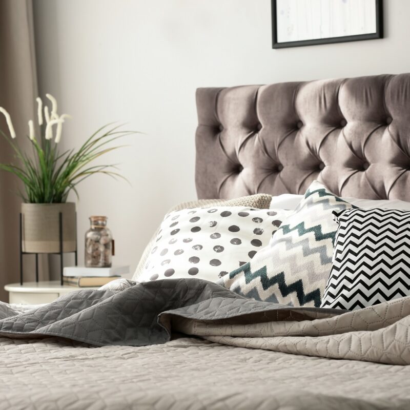 Comfortable bed with cushions in stylish bedroom interior