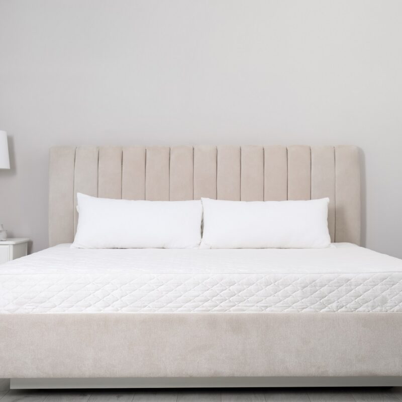 Comfortable bed with soft white mattress and pillows indoors